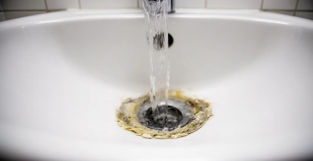 Eau s'écoulant lentement dans un lavabo avec dépôts de calcaire visibles