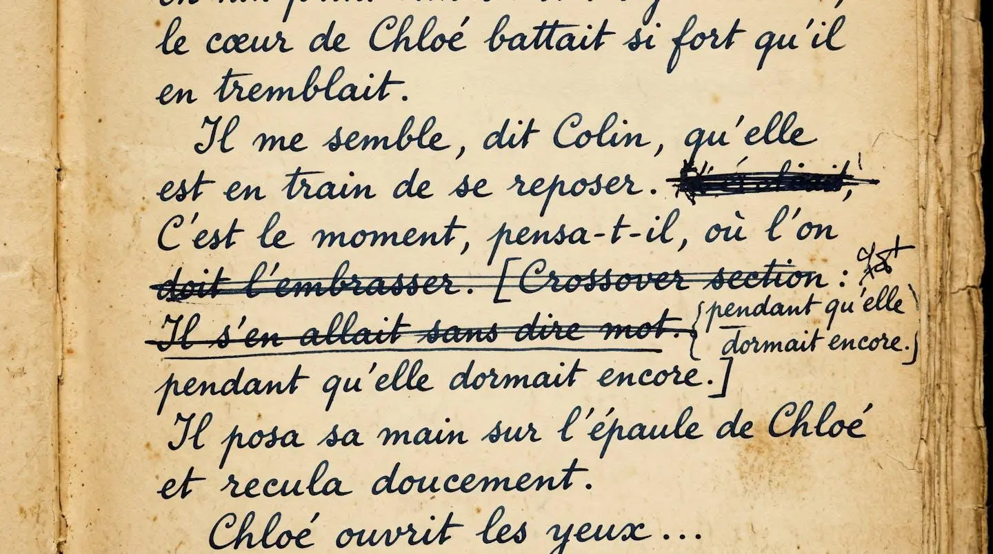 Gros plan sur une page manuscrite de L'Écume des jours montrant l'écriture cursive de Boris Vian avec ratures et corrections, papier vieilli photographié avec éclairage muséal