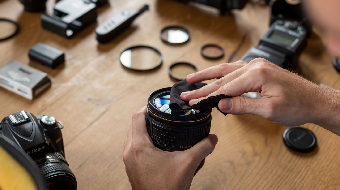 Technicien spécialisé inspectant objectifs cinéma professionnels de différentes focales sur établi de préparation, geste de contrôle qualité, bagues crantées et marquages T-stop visibles, espace de travail organisé de loueur parisien